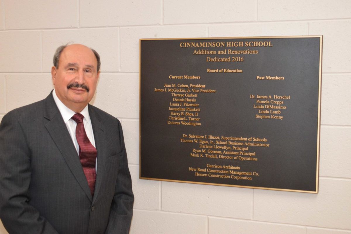 Dr. Illuzzi poses next to the plaque that honors the dedication of the new CHS building.