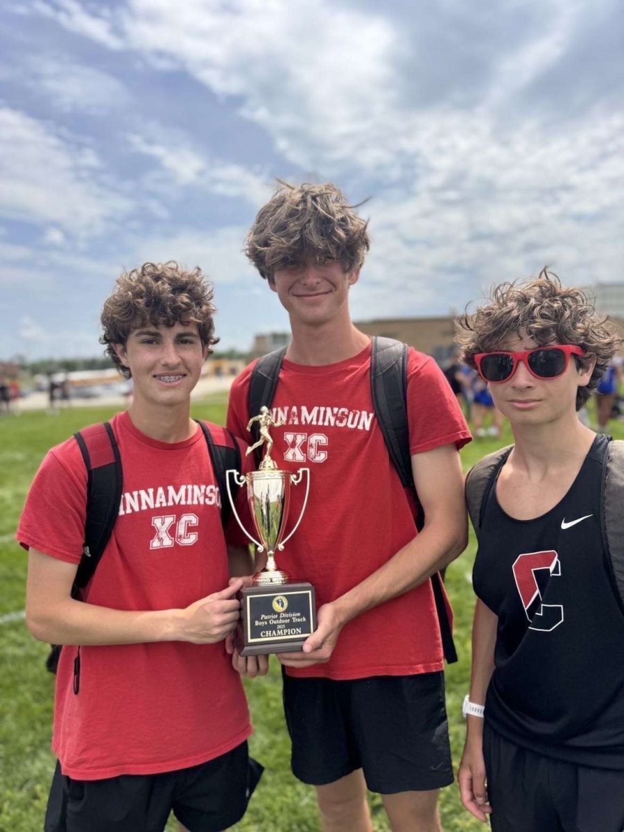 (Photo Courtesy of Robby Flynn) Three track athletes hold up trophy to show their success individually and for the whole team. 